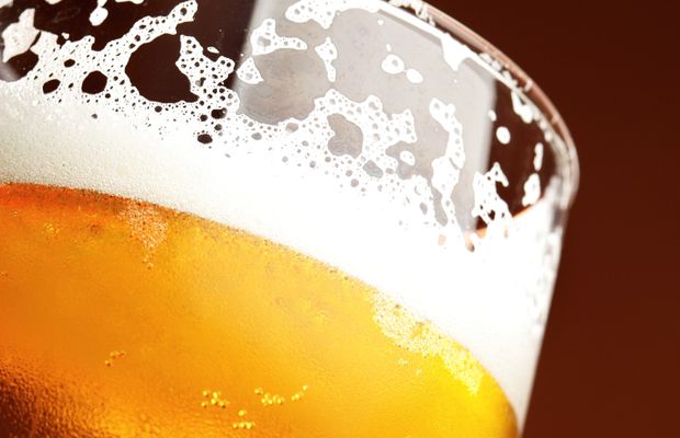 A glass of lager with its foam running down the side