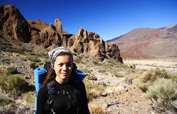A hiker with a loaded pack and chest strap among volcanic rock